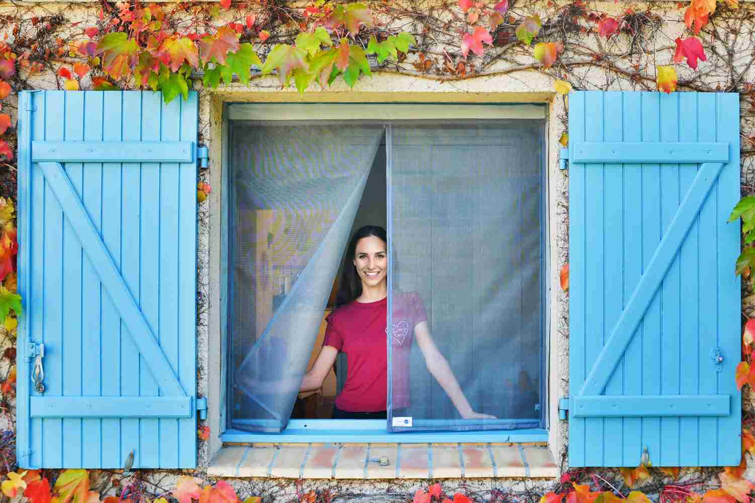Femme se tenant devant une moustiquaire ajustable pour fenêtre Tranquilisafe 