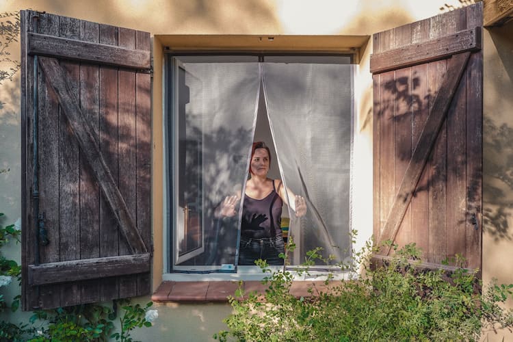 femme se tenant devant une fenêtre avec moustiquaire Tranquilisafe